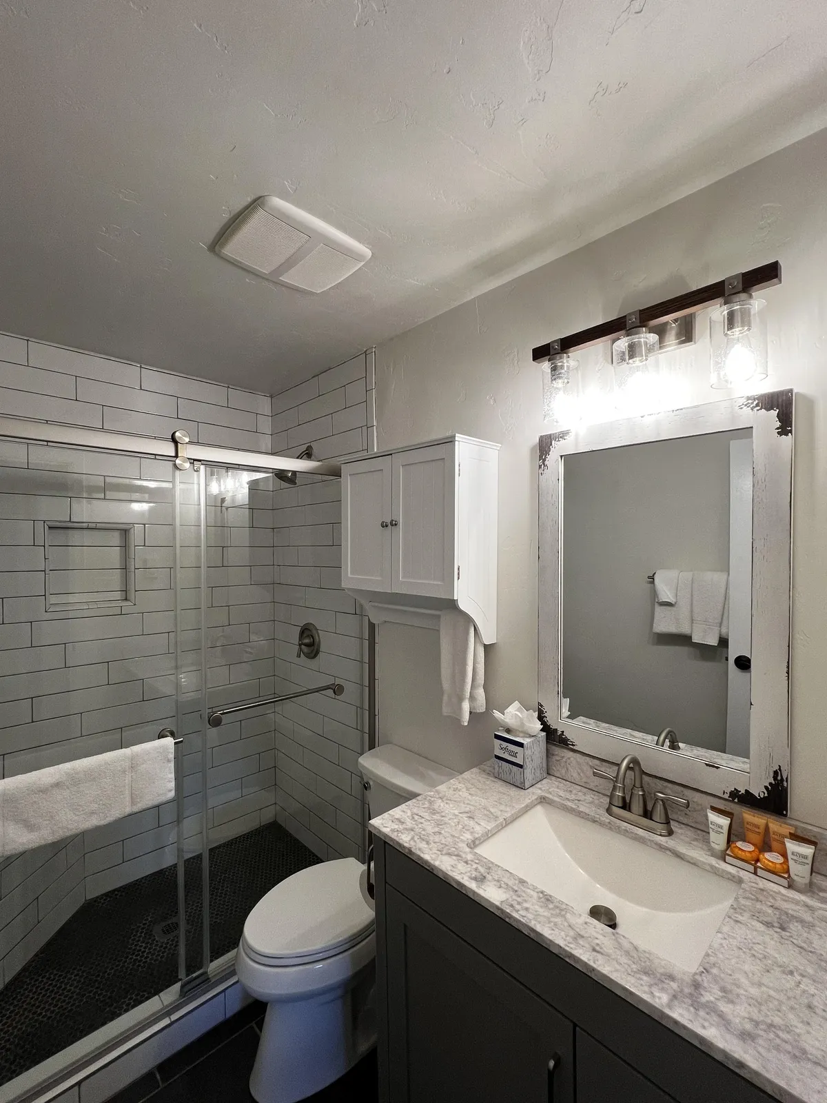 A stylish bathroom featuring a spacious shower area, modern vanity with sink, well-lit mirror, and tasteful light fixtures. The environment feels fresh, clean, and perfect for rejuvenation after a mountain adventure.